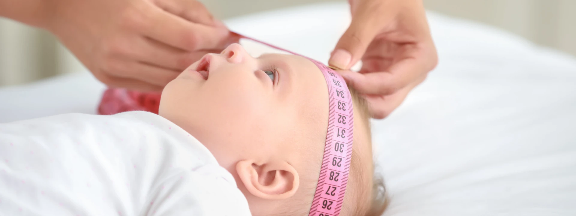 Médica medindo a cabeça da criança com uma fita métrica